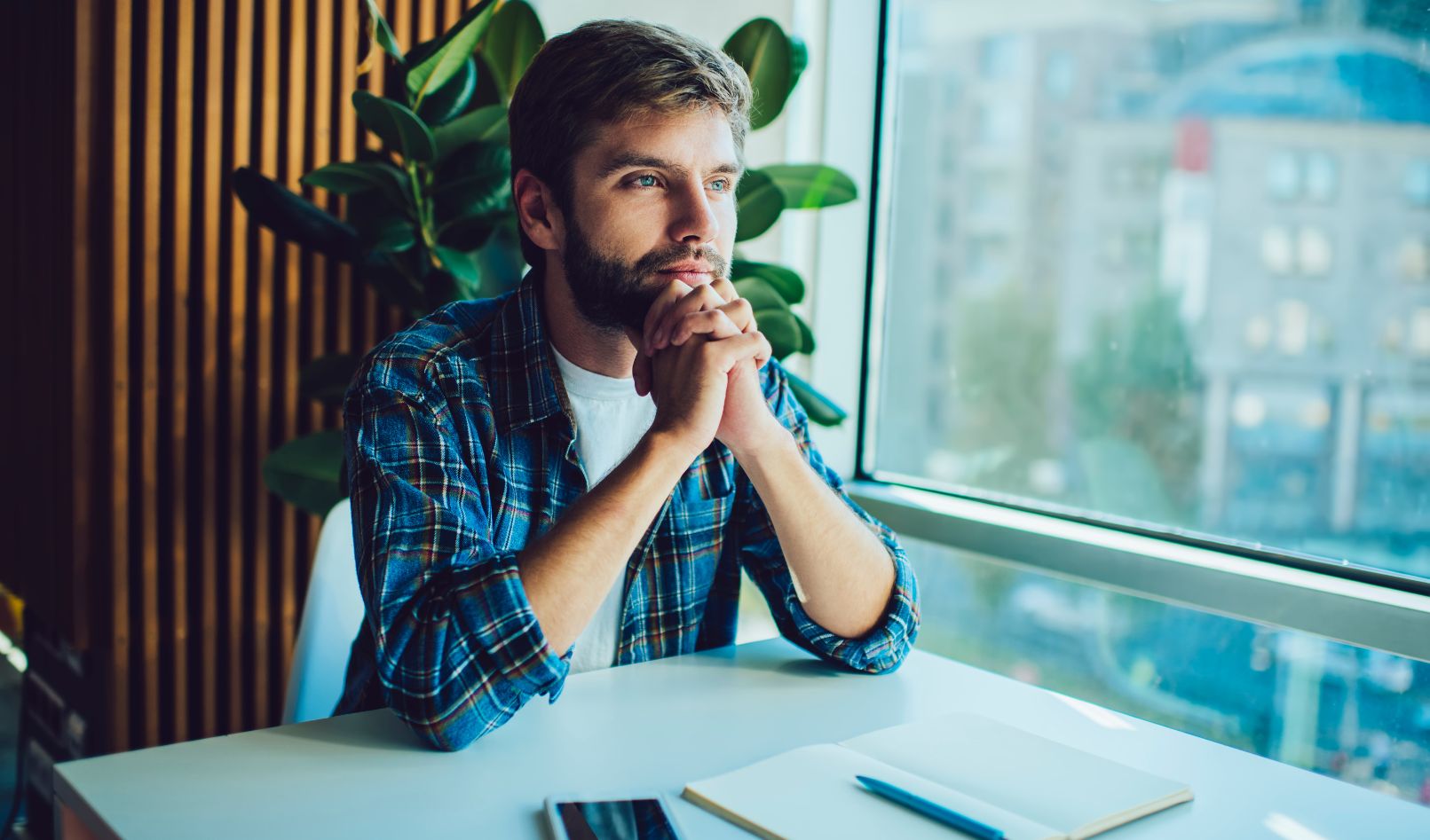 A male freelance blogger sitting at a table trying to overcome writer's block.