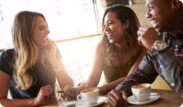 Three friends at a coffee shop brainstorming how to reignite their passion for blogging.