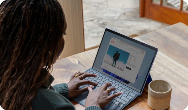 Woman sitting at a table typing on her laptop trying to figure out her blog niche.
