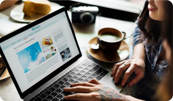 A woman blogger sitting at a desk typing on a laptop crafting a blog post that ranks.